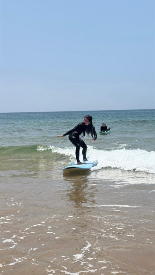 Student standing up on a wave and smiling