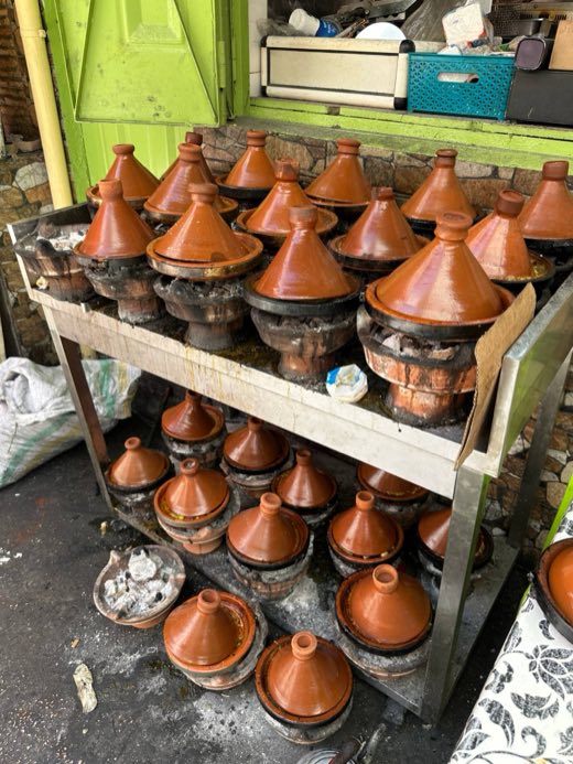 Tajines cooking over charcoal at a street stall