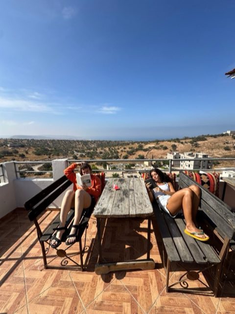 Two guests reading on the rooftop terrace with views to the sea